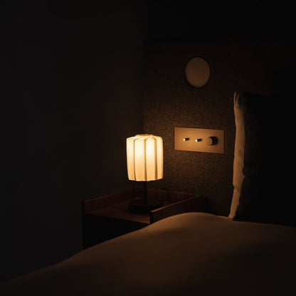 Japanse papieren tafellamp "Bloem van Licht tutu met standaard" verlicht op een houten nachtkastje