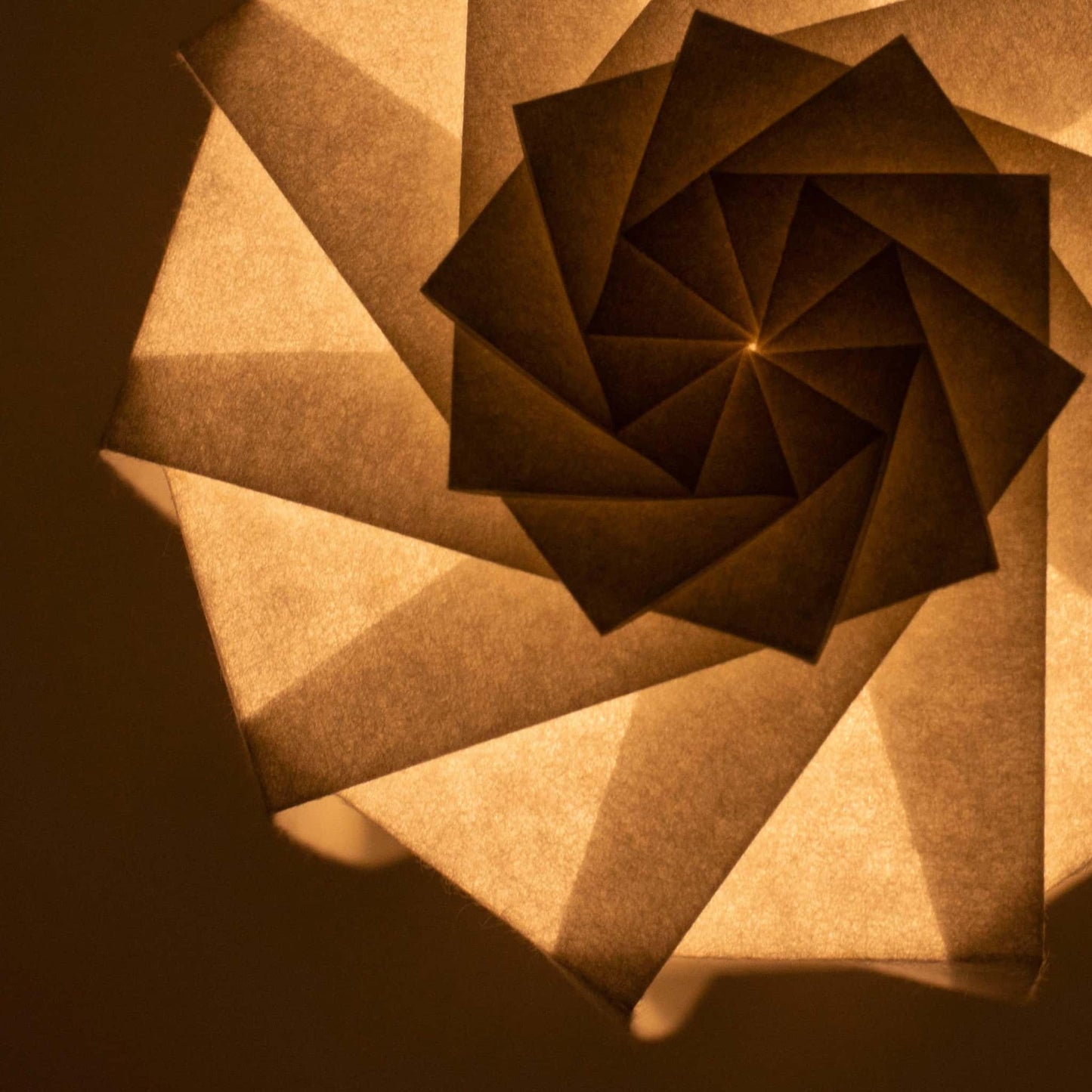 Frameloze Japanse papieren tafellamp, vervaardigd met traditionele Kyo-hyogu en origami-technieken, met een uniek verlicht origami-patroon, 's nachts op een tafel geplaatst.