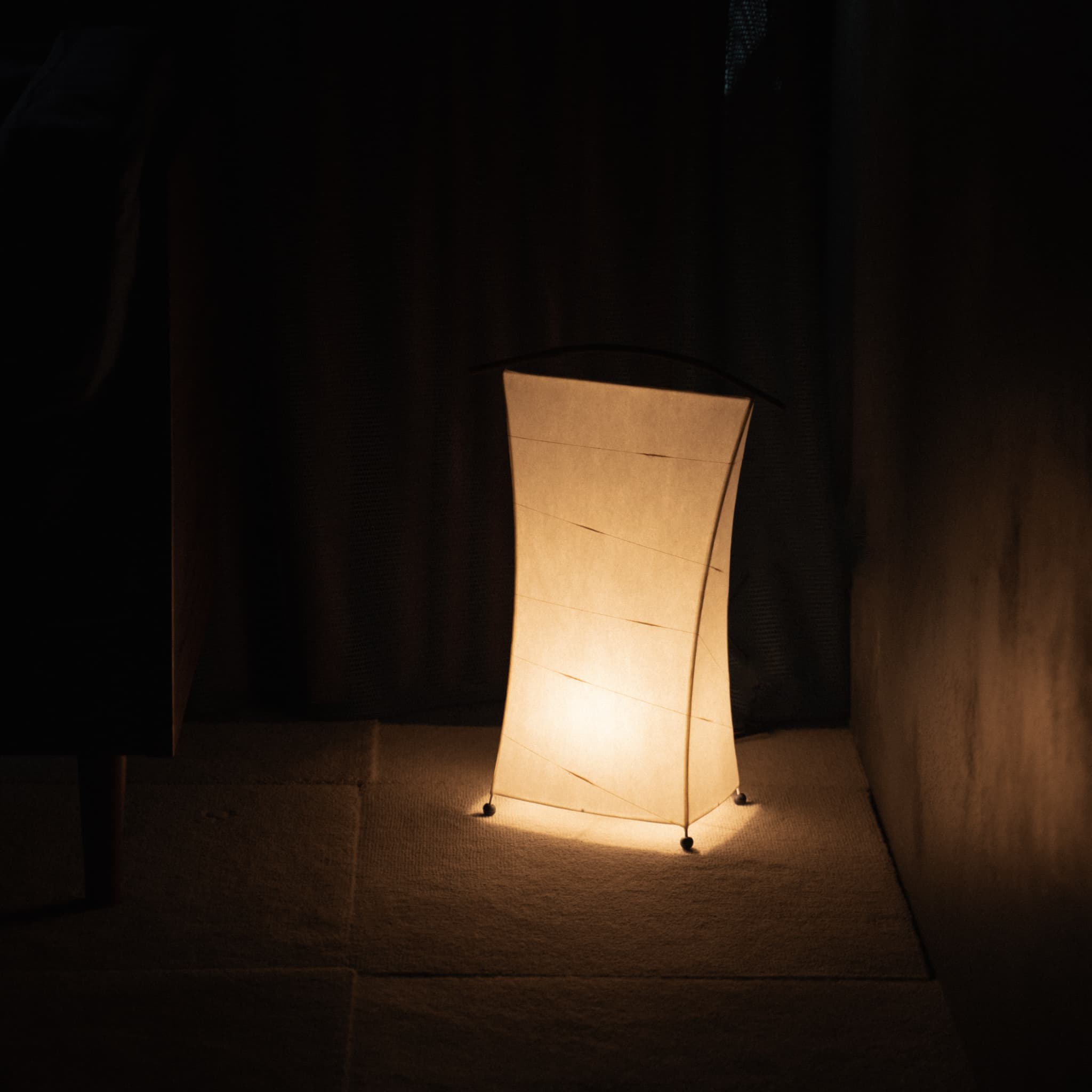 "Lampe de sol japonaise en papier « NOW » diffusant une lumière chaude dans une pièce faiblement éclairée"