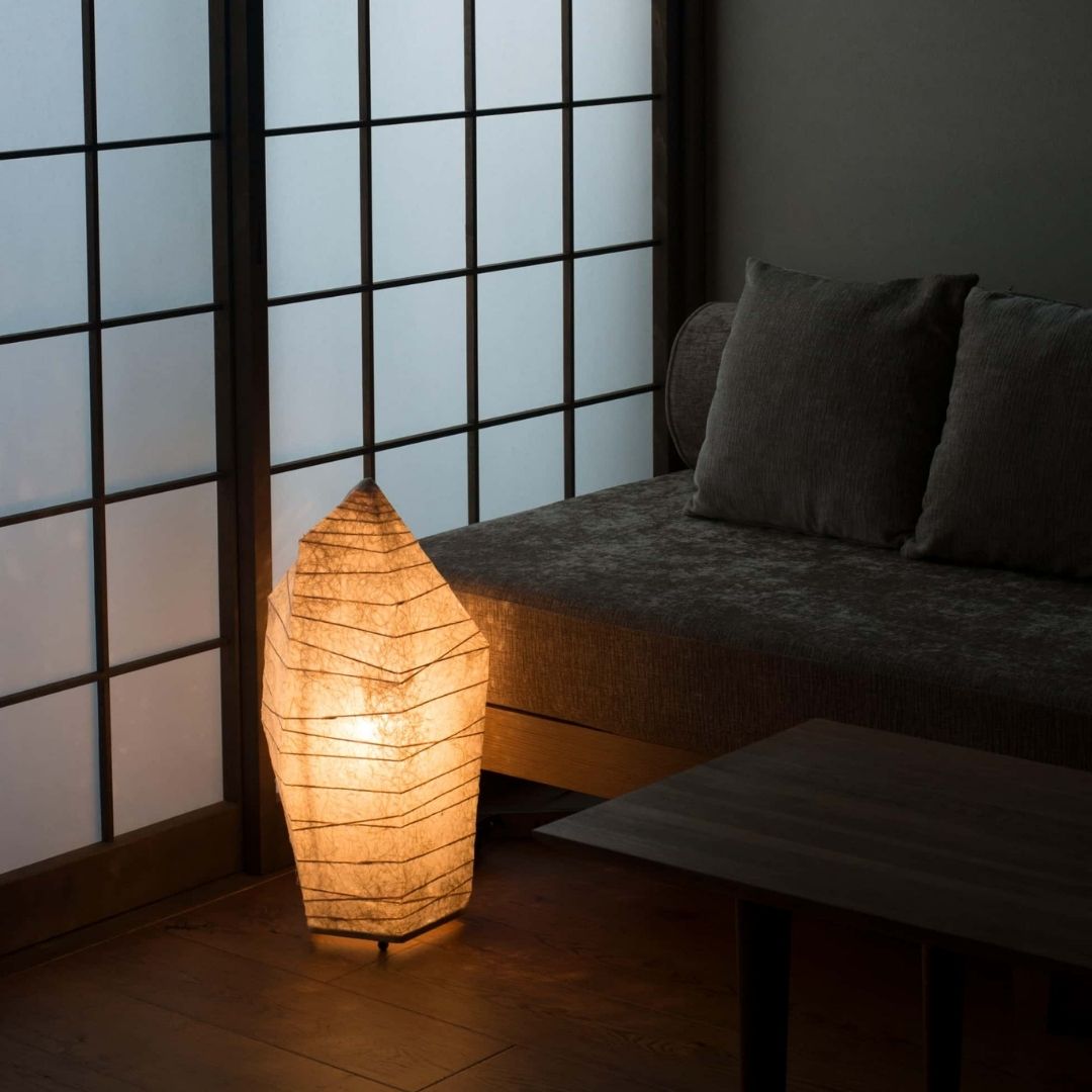 Japanese floor lamp "PAPAER STONE" emitting a warm glow in a dimly lit Japanese-style living room