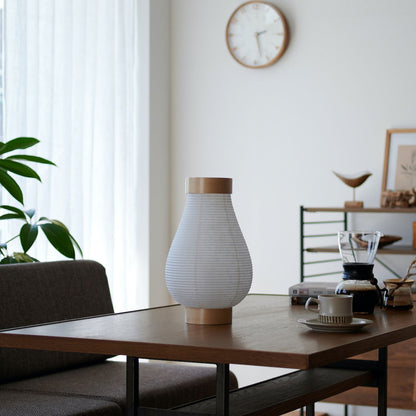 "Een traditionele Japanse papieren lantaarnlamp op een tafel in een woonkamer in Japandi-stijl"