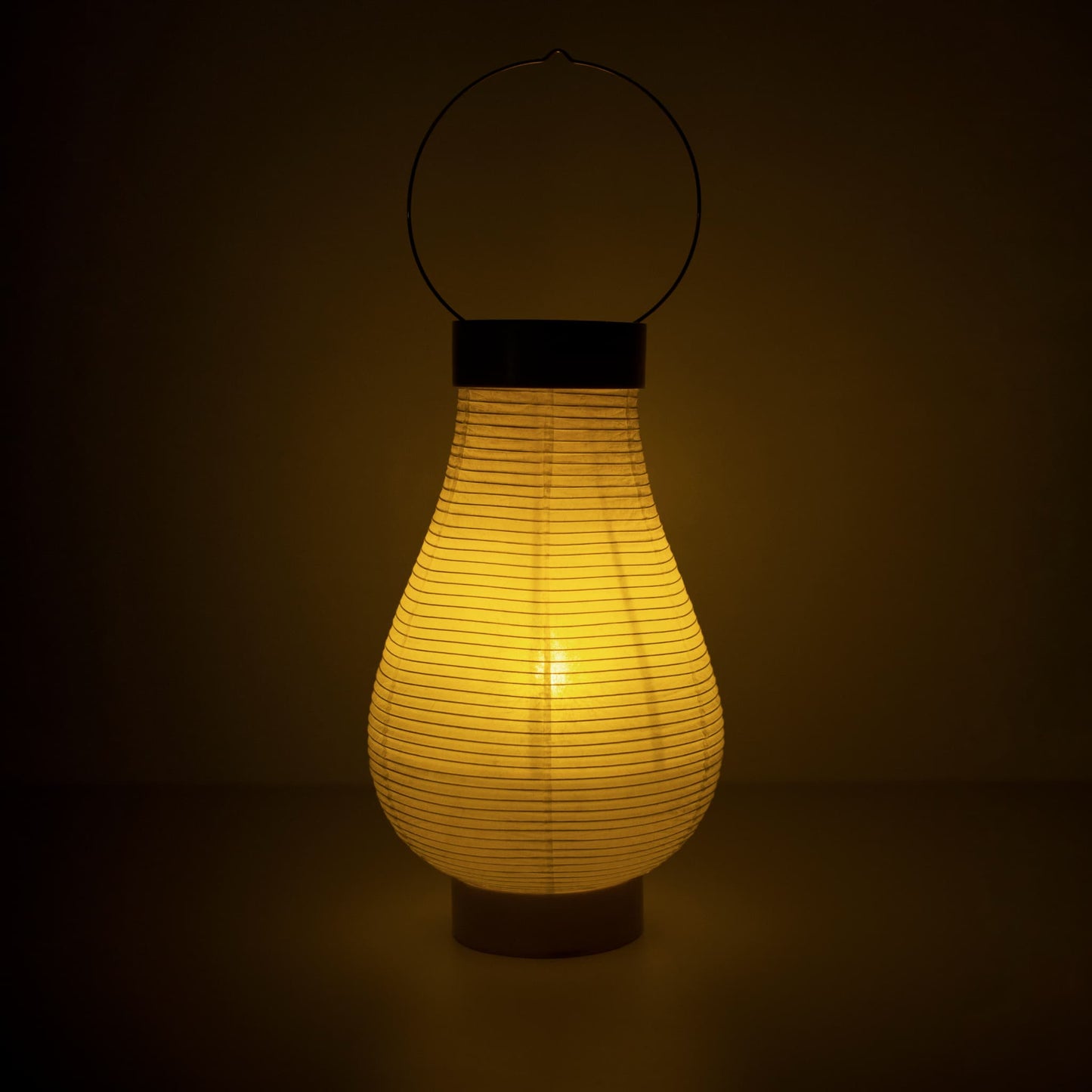 Een traditionele Japanse papieren lantaarnlamp die warm licht uitstraalt in een donkere kamer