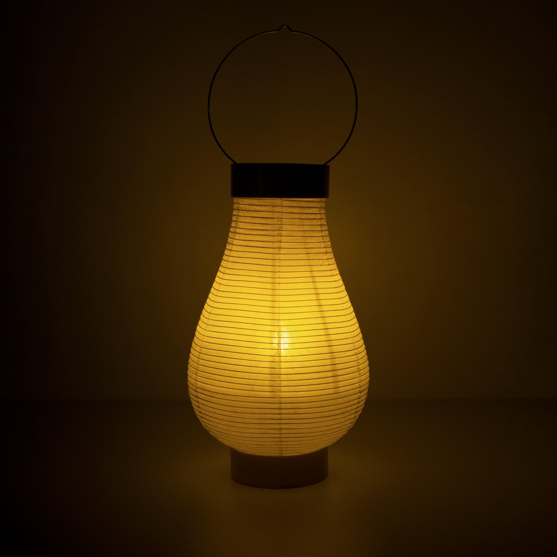 Een traditionele Japanse papieren lantaarnlamp die warm licht uitstraalt in een donkere kamer