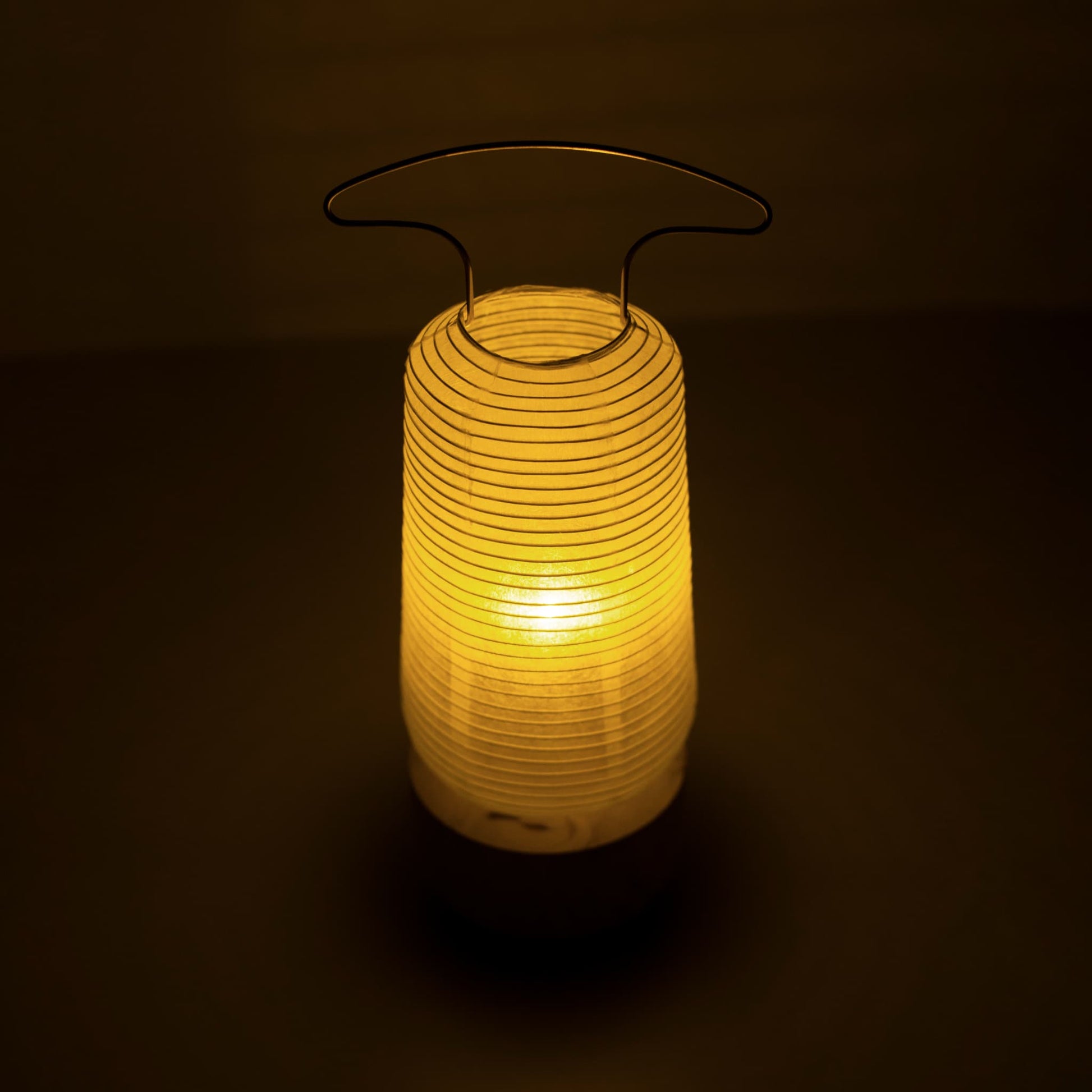 "Een traditionele Japanse papieren lantaarn die warm licht uitstraalt in een schemerige kamer"