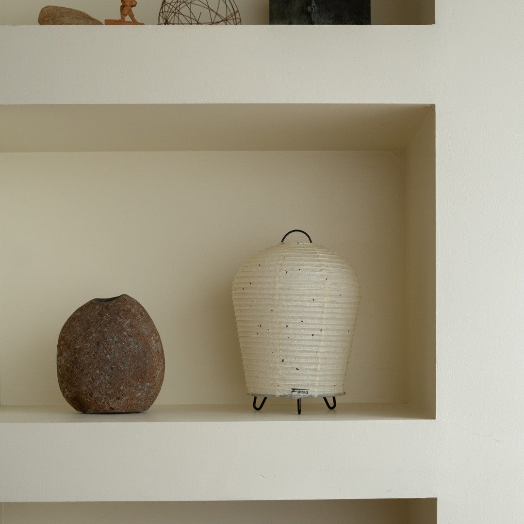 "Japanse Papieren Tafellamp \"PAPERSON 01\" op een witte plank in een woonkamer in Japandi-stijl – Unieke papieren nachtkastlamp voor slaapkamer"