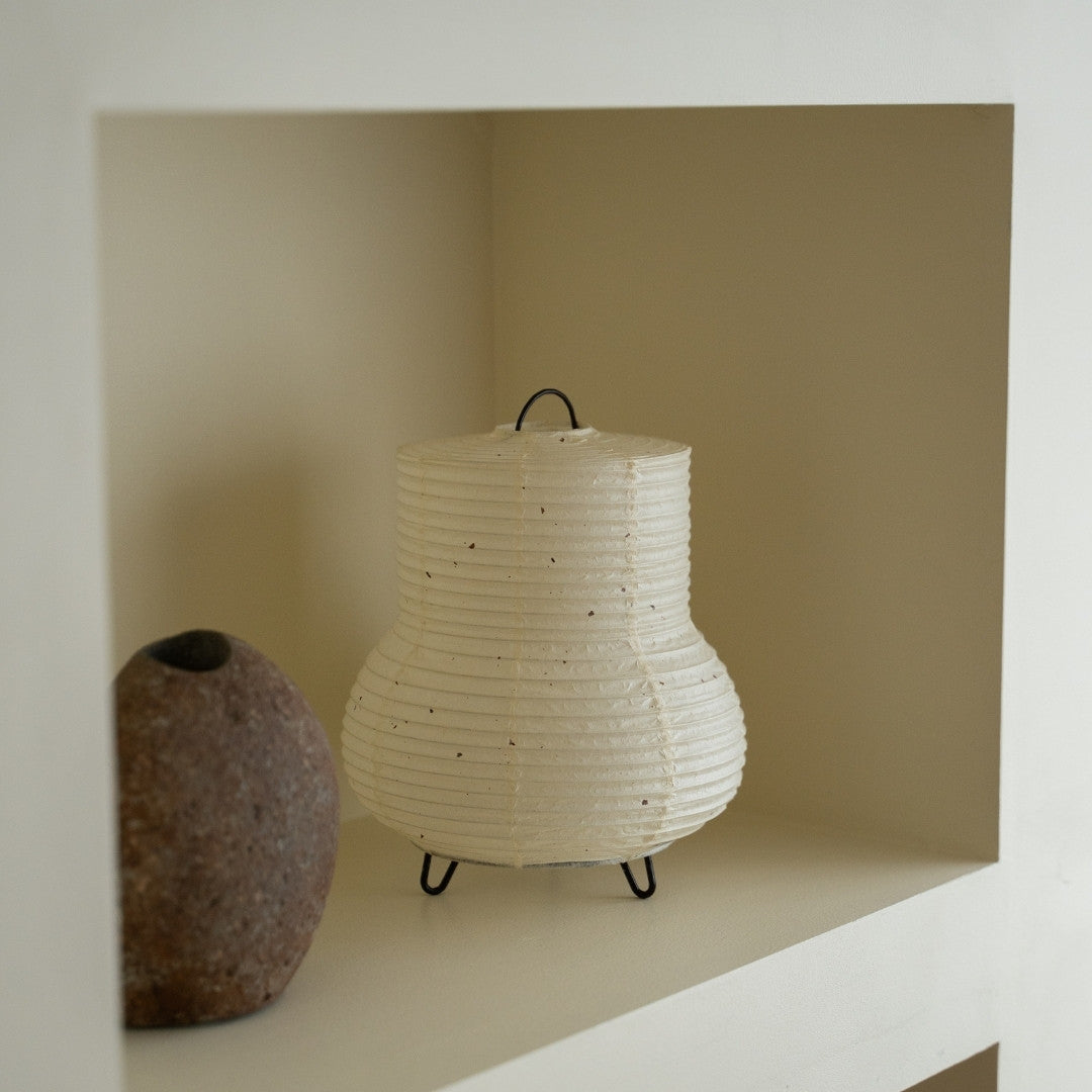 "Japanse papieren tafellamp \"PAPERSON 02\" op een witte plank in een woonkamer in Japandi-stijl – Unieke papieren tafellamp voor Japandi-interieur"