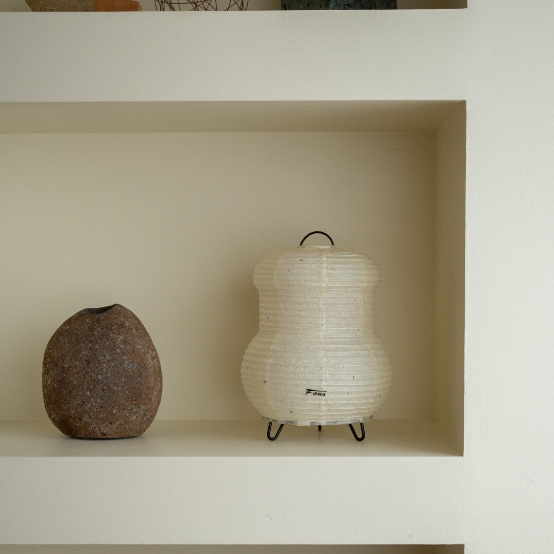 "Japanse papieren tafellamp \"PAPERSON 03\" op een witte plank in een woonkamer in Japandi-stijl – Unieke papieren tafellamp voor een Japandi-interieur"