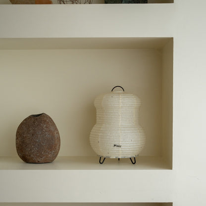 "Japanse papieren tafellamp \"PAPERSON 03\" op een witte plank in een woonkamer in Japandi-stijl – Unieke papieren tafellamp voor een Japandi-interieur"