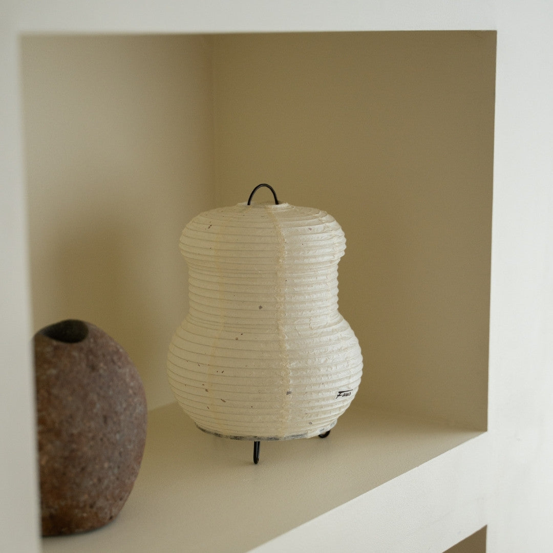 "Japanse papieren tafellamp \"PAPERSON 03\" op een witte plank in een woonkamer in Japandi-stijl – Papieren tafellamp voor Japandi-interieur"