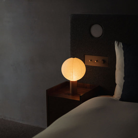 A Japanese paper touch lamp "TORCHIN CIRCLE" on a bedside table. 