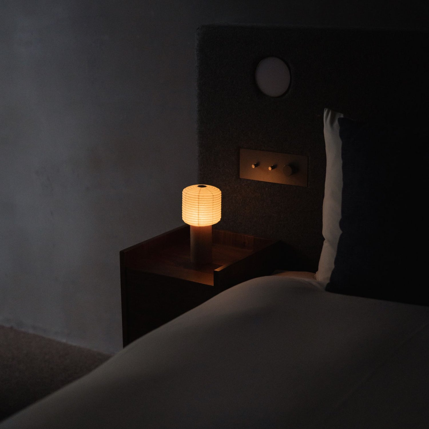 "Eine japanische Papier-Touch-Lampe „TORCHIN SQUARE“ auf einem Nachttisch." 