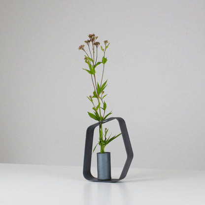 A minimalist black iron vase crafted using traditional Japanese roof tile making techniques, paired with a black wood frame.