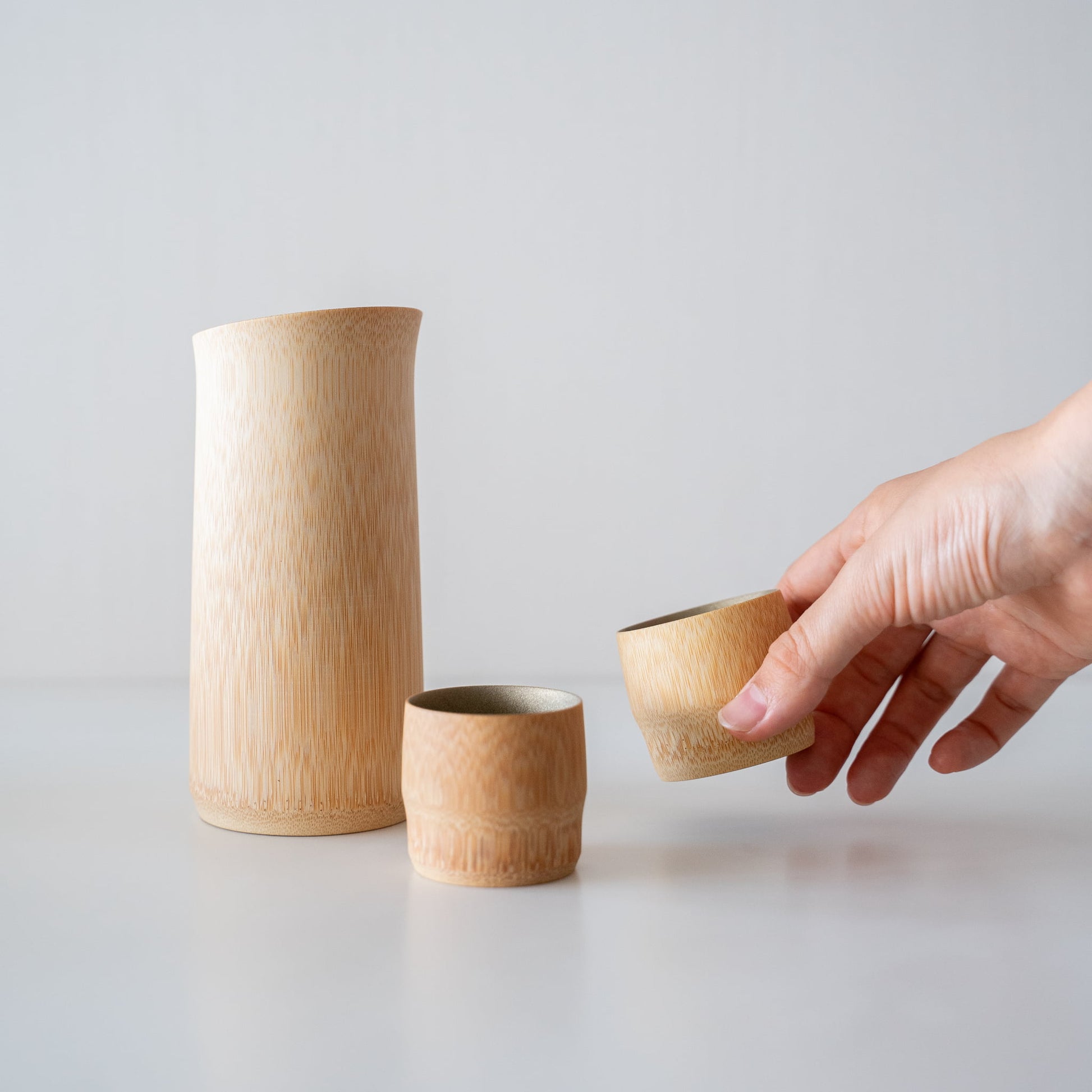 "Hand hält einen Bambus-Sakebecher, der mit traditionellen Techniken aus Kyoto, Japan, gefertigt wurde."
