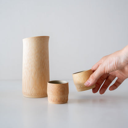 "Hand hält einen Bambus-Sakebecher, der mit traditionellen Techniken aus Kyoto, Japan, gefertigt wurde."