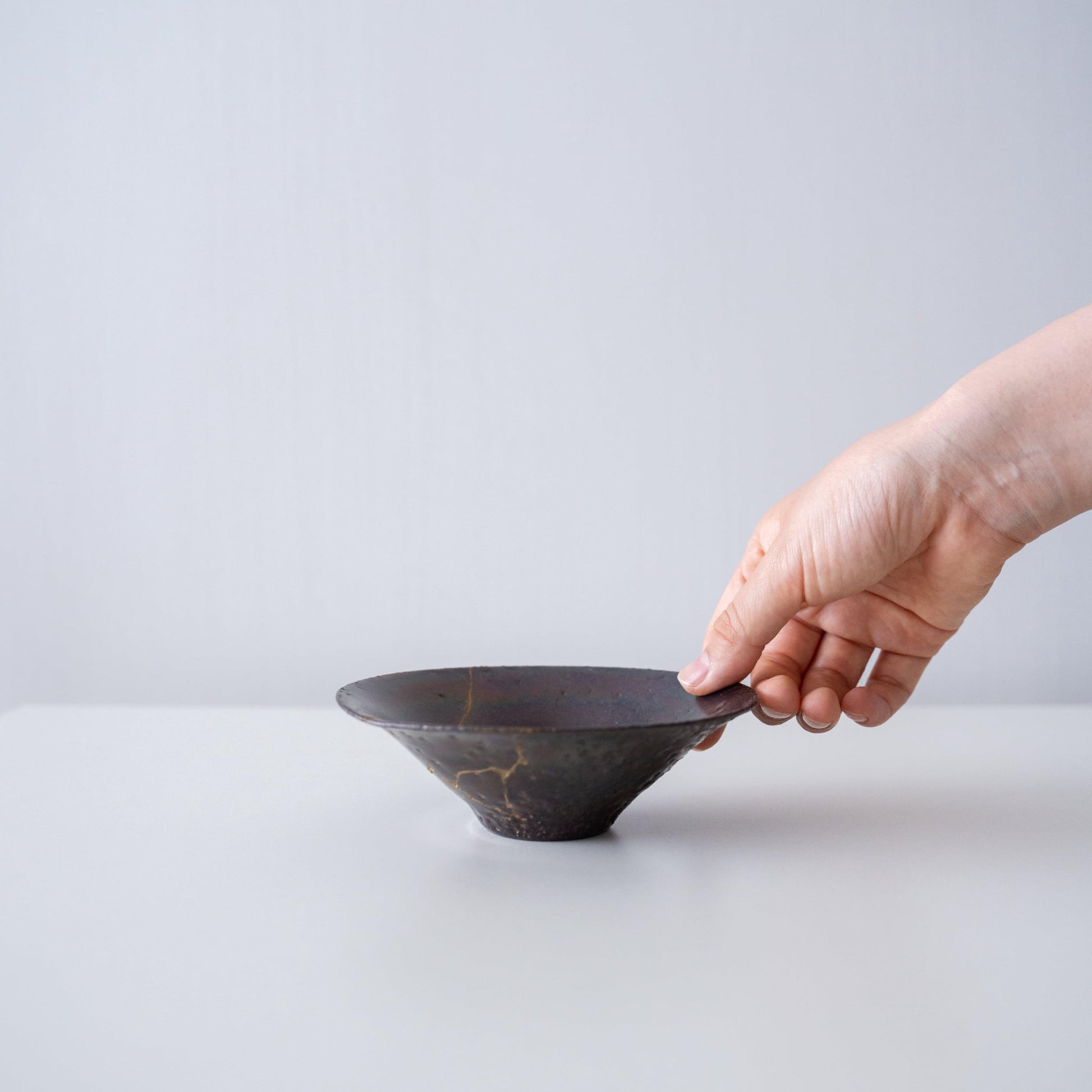 "Hand die een bladvormige kom vasthoudt, gerepareerd met Kintsugi, een traditionele Japanse techniek."