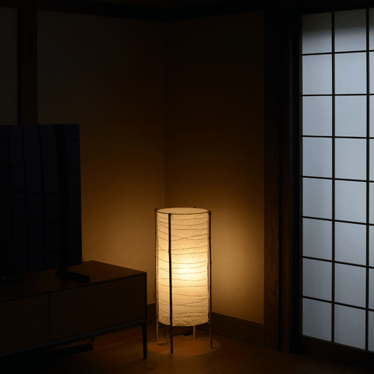 Japanese washi paper floor lamp with bamboo frame, placed in a traditional room, emitting warm light in Japandi living room.