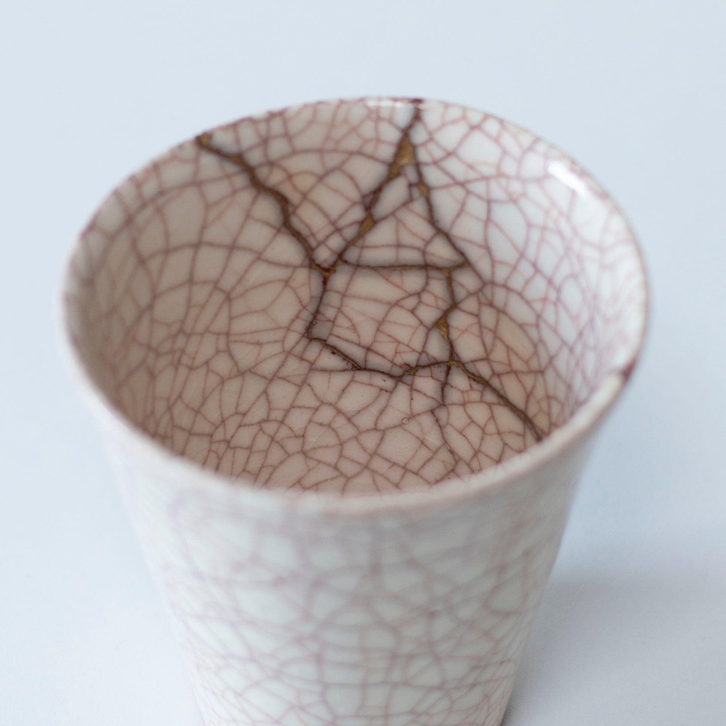 Hvid kop repareret med Kintsugi, en traditionel japansk teknik, præsenteret i en paulownia-trækasse med inskriptionen "Kintsugi".