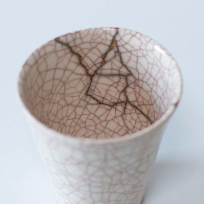 Hvid kop repareret med Kintsugi, en traditionel japansk teknik, præsenteret i en paulownia-trækasse med inskriptionen "Kintsugi".
