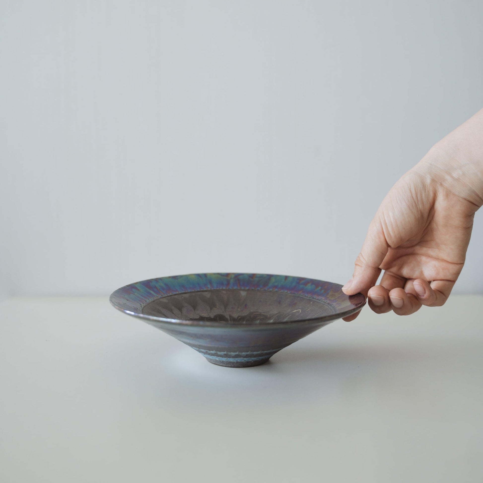 "Hand hält Kintsugi-Schale „Blaue Rosen-Nebel“, zeigt ihre Größe und wie sie in die Hand passt"