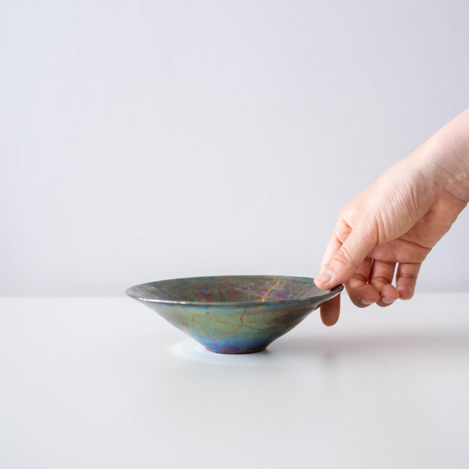 Main tenant un bol Kintsugi « Green Nebula », montrant sa taille et sa prise en main