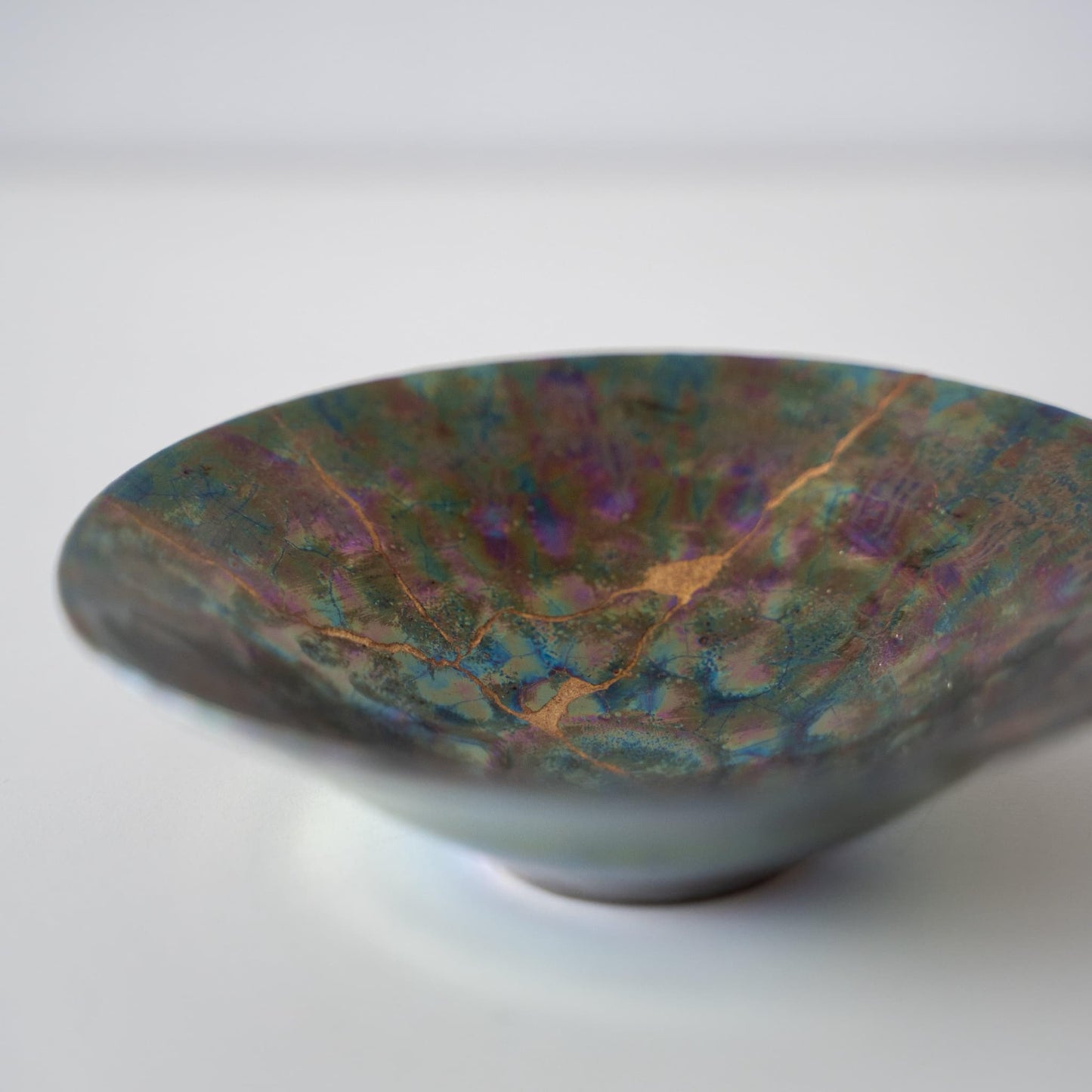 Gros plan du bol Kintsugi "Nébuleuse Verte" sur le côté, mettant en valeur les réparations Kintsugi complexes