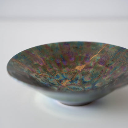 Gros plan du bol Kintsugi "Nébuleuse Verte" sur le côté, mettant en valeur les réparations Kintsugi complexes