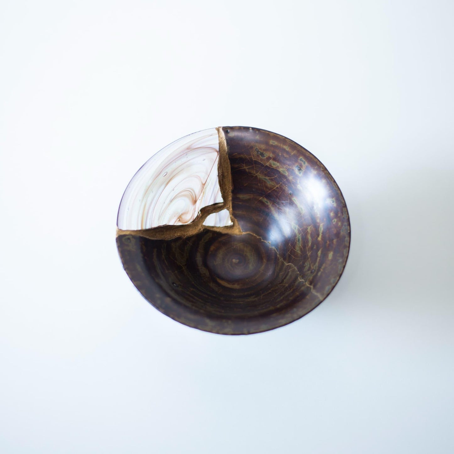 Eine Kintsugi-reparierte Schale mit einer schönen blauen Glasfüllung, die sich von einer warmbraunen Glasur abhebt und an die Rinde eines Kirschbaums erinnert.