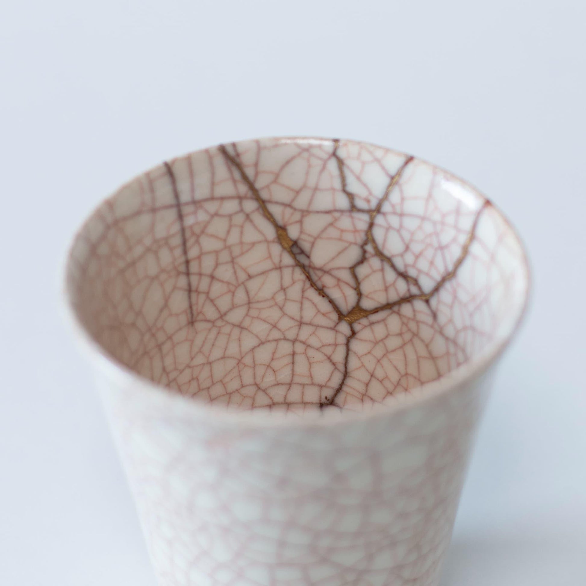Et nærbillede af kintsugi-reparationen på indersiden af en hvid keramik kop, der viser skønheden i uperfekthed.