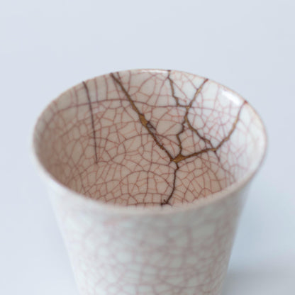 Et nærbillede af kintsugi-reparationen på indersiden af en hvid keramik kop, der viser skønheden i uperfekthed.
