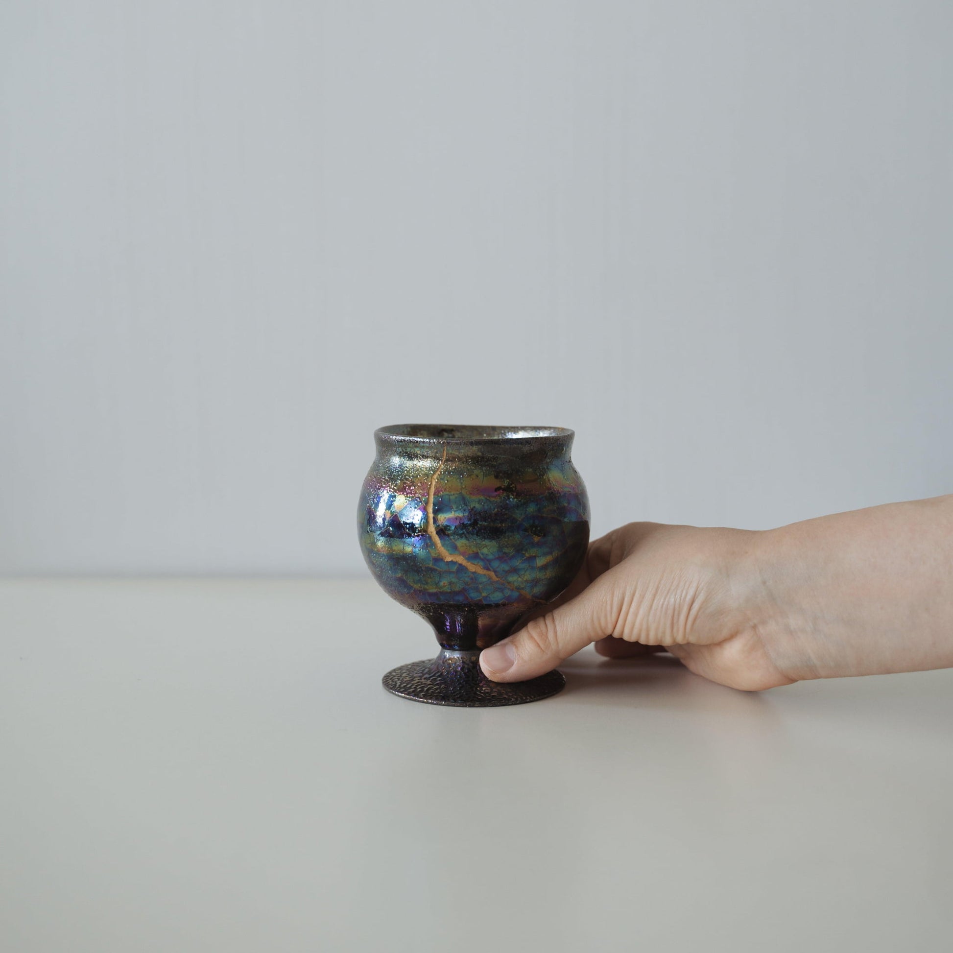 Hånd, der holder Kintsugi-pokal "The Dawn Starry Sky", der viser dens størrelse og hvordan den passer i hånden
