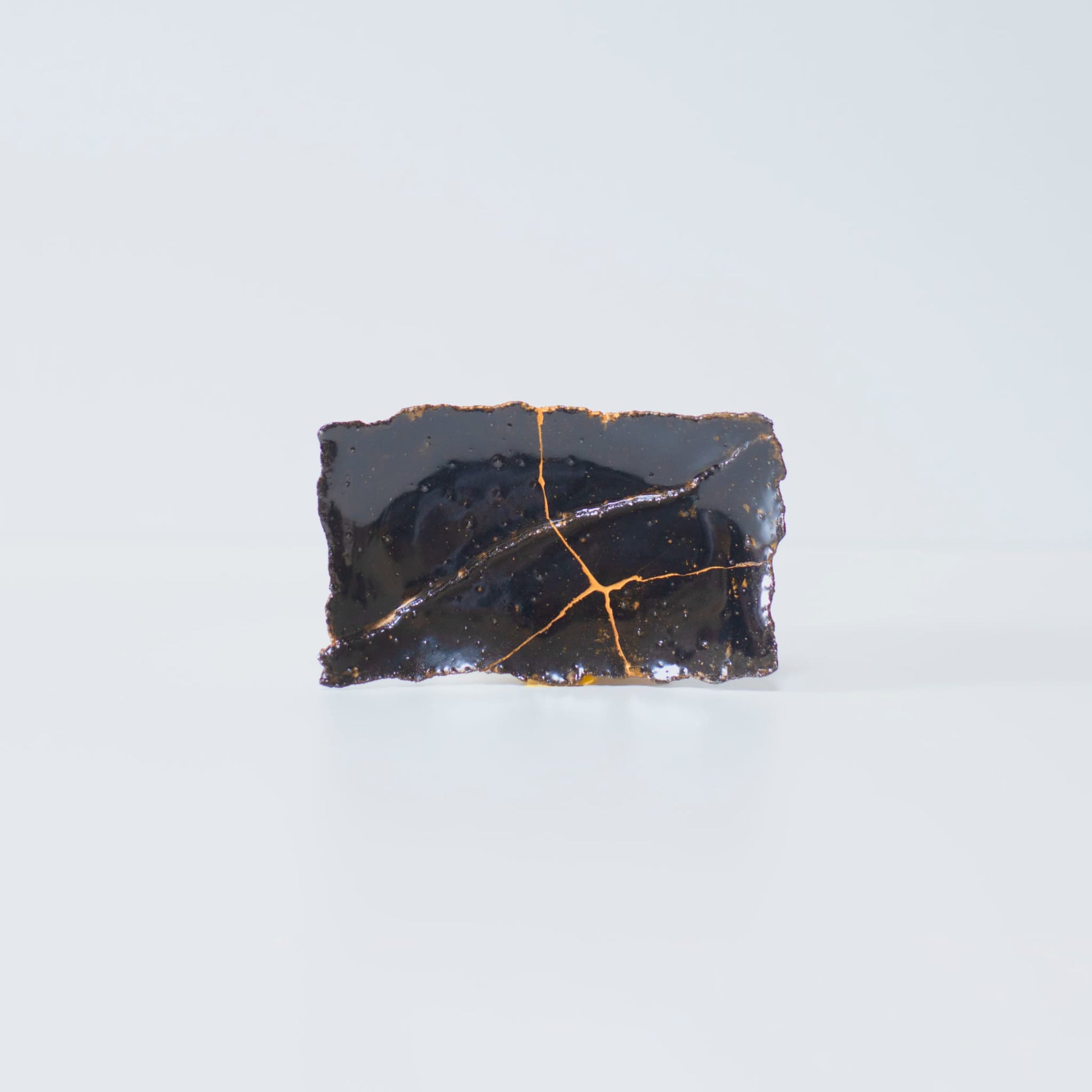 Zijaanzicht van Kintsugi-bord "Tenmoku" Zwart 01 op een witte achtergrond