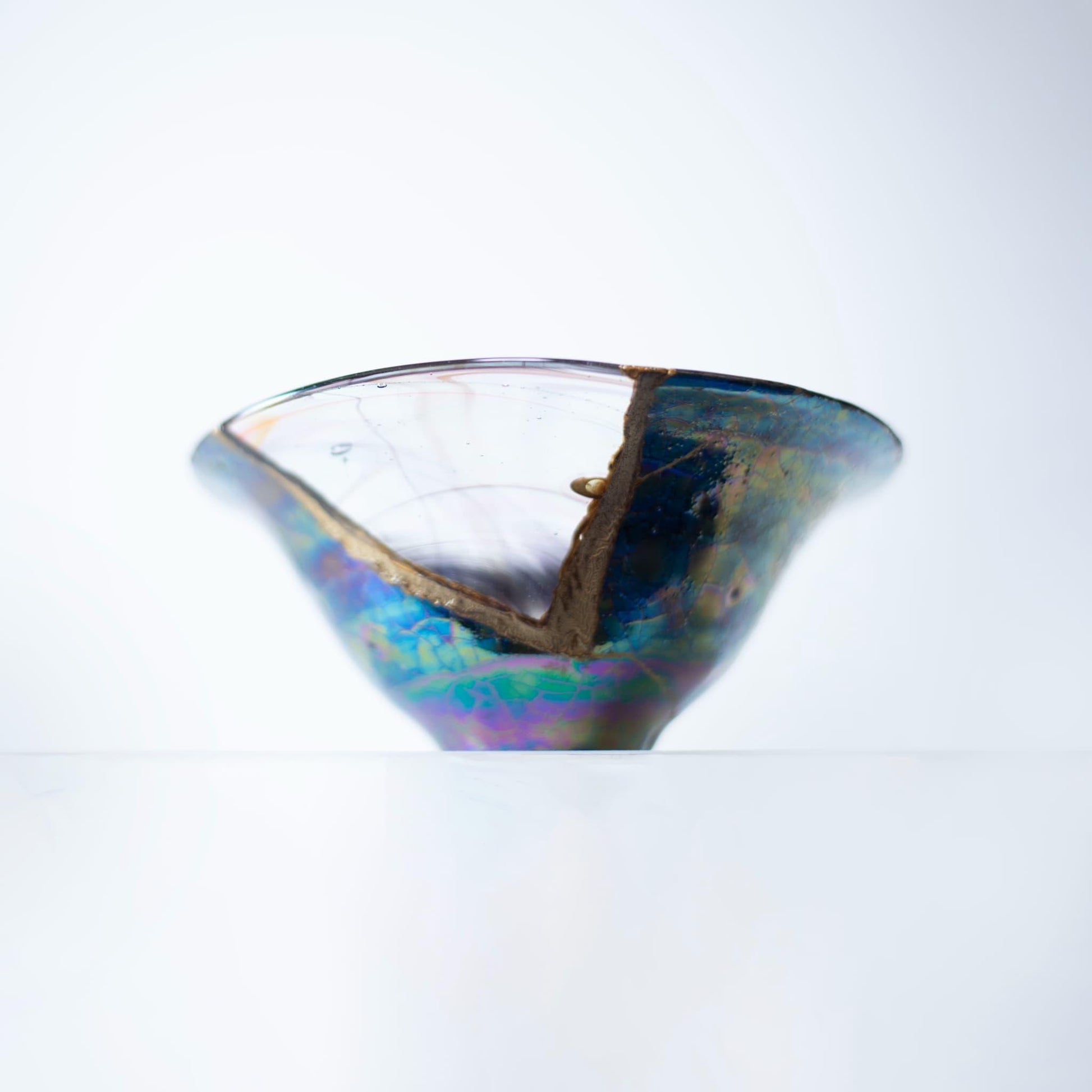 Et forstørret billede af en Kintsugi-skål, der fremhæver de indviklede detaljer af reparationen og den smukke farvekombination af kirsebærblomst og himmelblå.
