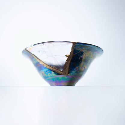 Et forstørret billede af en Kintsugi-skål, der fremhæver de indviklede detaljer af reparationen og den smukke farvekombination af kirsebærblomst og himmelblå.