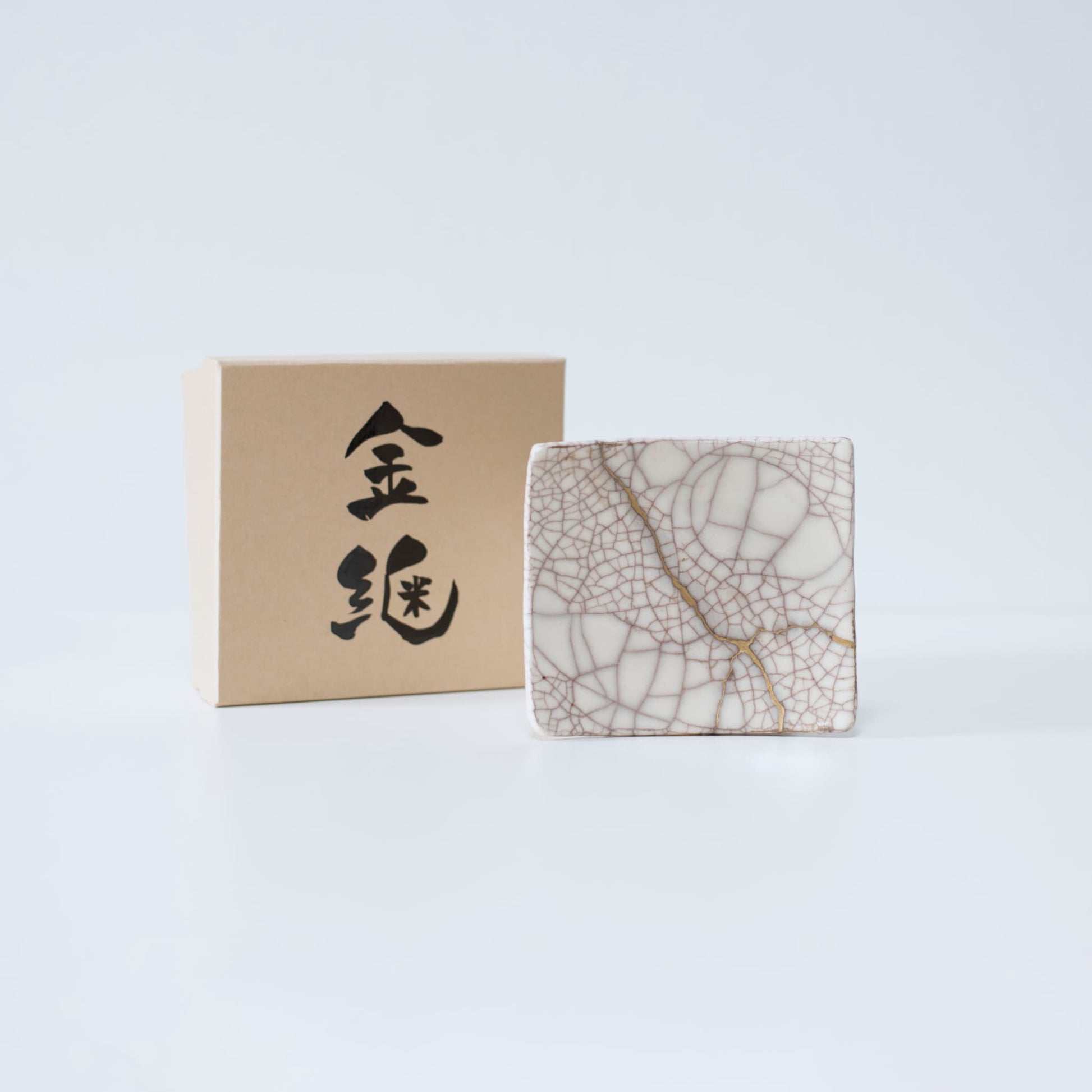 Sidevisning af Kintsugi firkantet tallerken "Vermilion Crackle" 01 med etui på en hvid baggrund