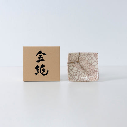 "Zijaanzicht van Kintsugi vierkante schaal 'Vermilion Crackle' 06 met koffer op een witte achtergrond"