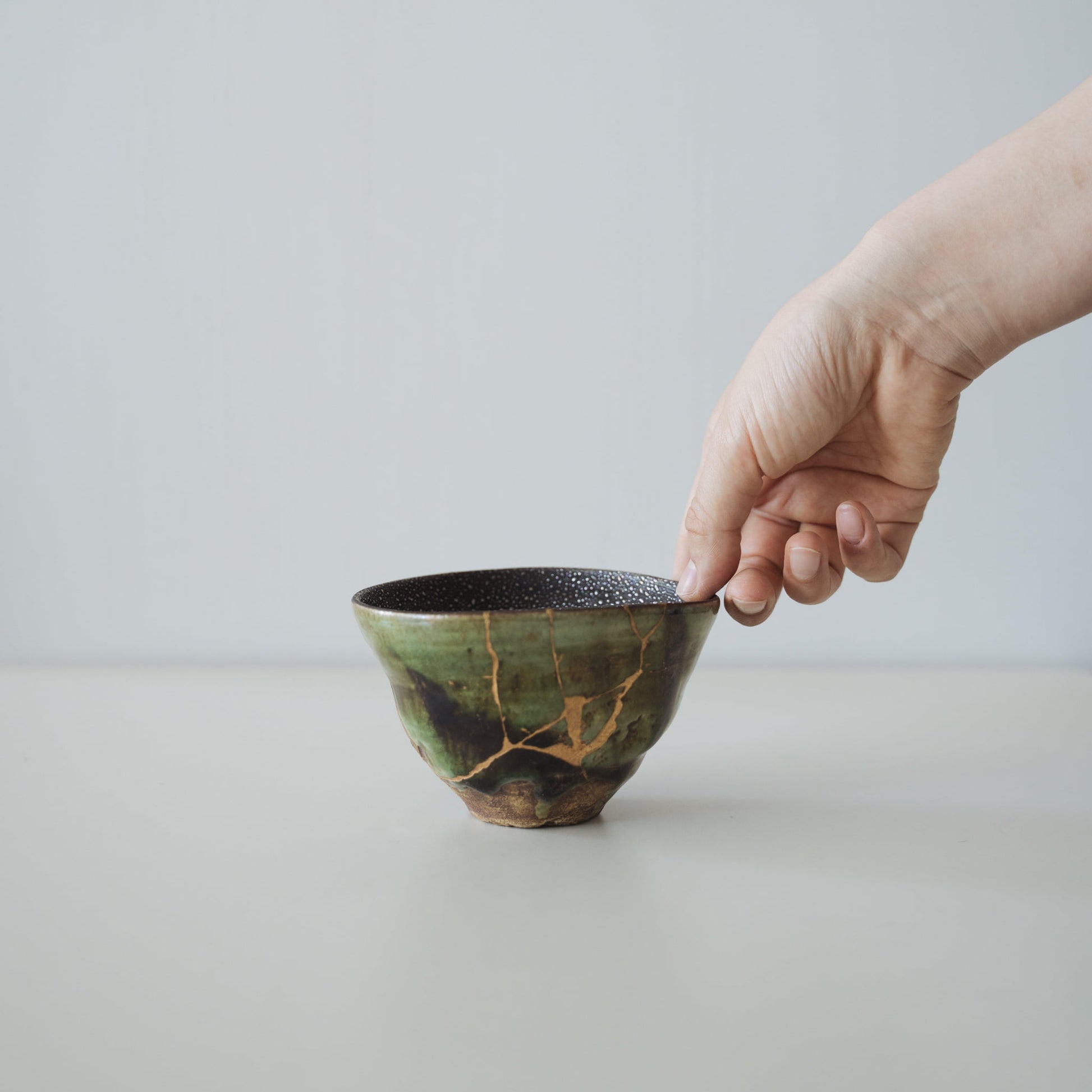 Hånd, der holder Kintsugi-tekop "Stjernehimmel og Dal", der viser dens størrelse og hvordan den passer i hånden