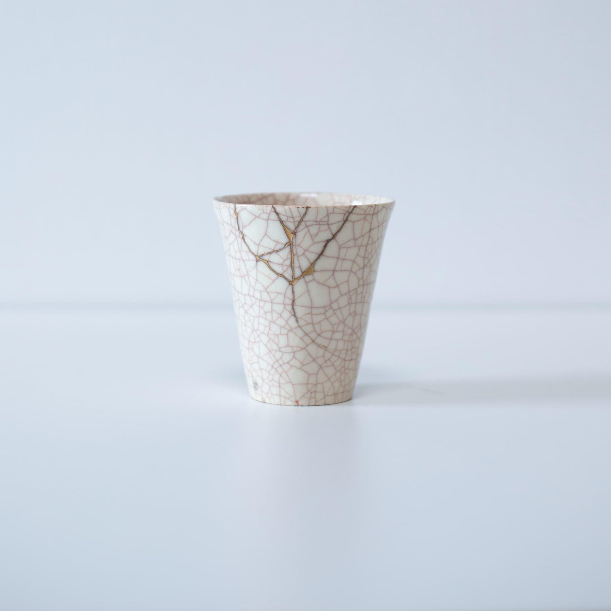 Kintsugi-repareret hvid kop og gaveæske af paulownia-træ, der symboliserer den japanske æstetik med at finde skønhed i ufuldkommenhed.