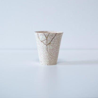 Kintsugi-repareret hvid kop og gaveæske af paulownia-træ, der symboliserer den japanske æstetik med at finde skønhed i ufuldkommenhed.