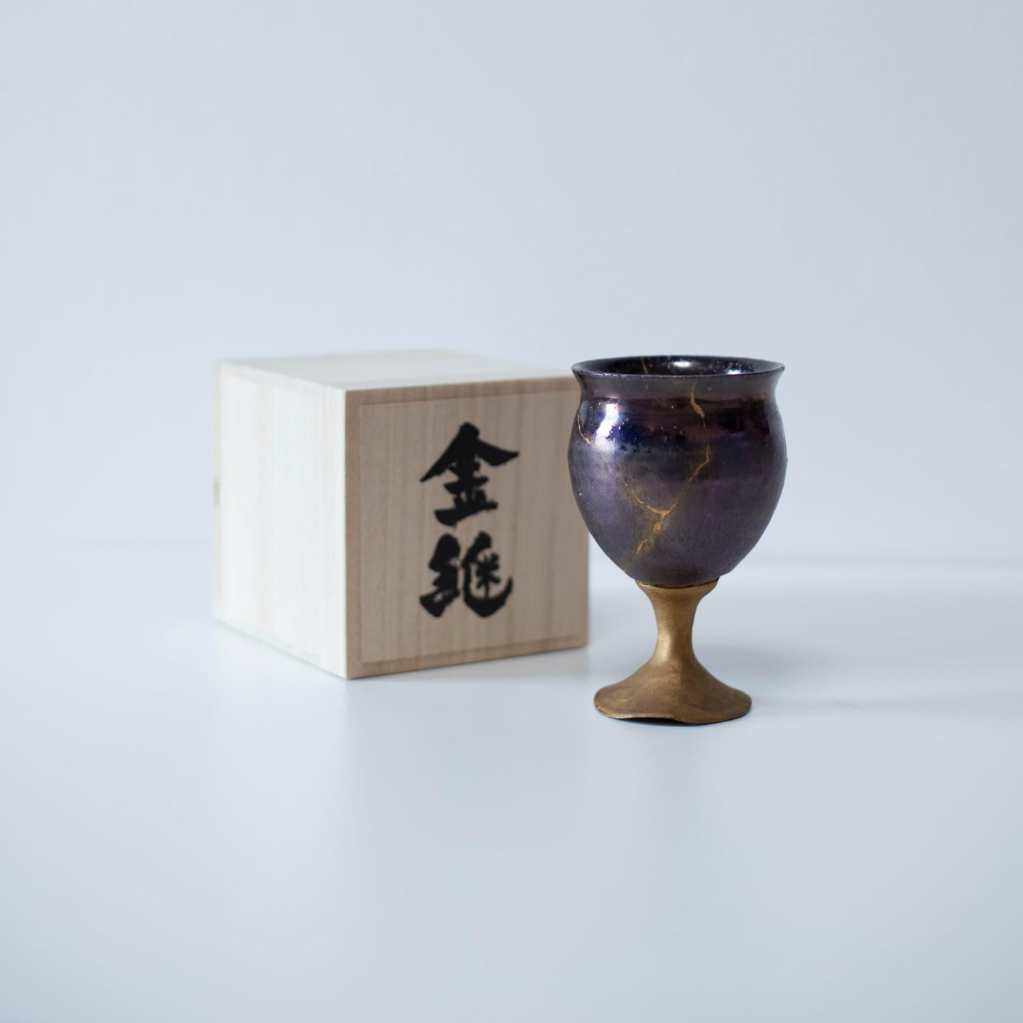 Magenta kintsugi vinglas repareret med Kintsugi, en traditionel japansk teknik, præsenteret i en paulownia trækasse med inskriptionen "Kintsugi".