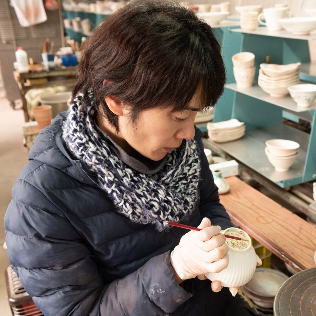 Buzan Kiln-håndværker maler i hånden en japansk Mino Ware matcha-skål i sit keramikstudie, der viser delikat penselstrøg og traditionelt håndværk.