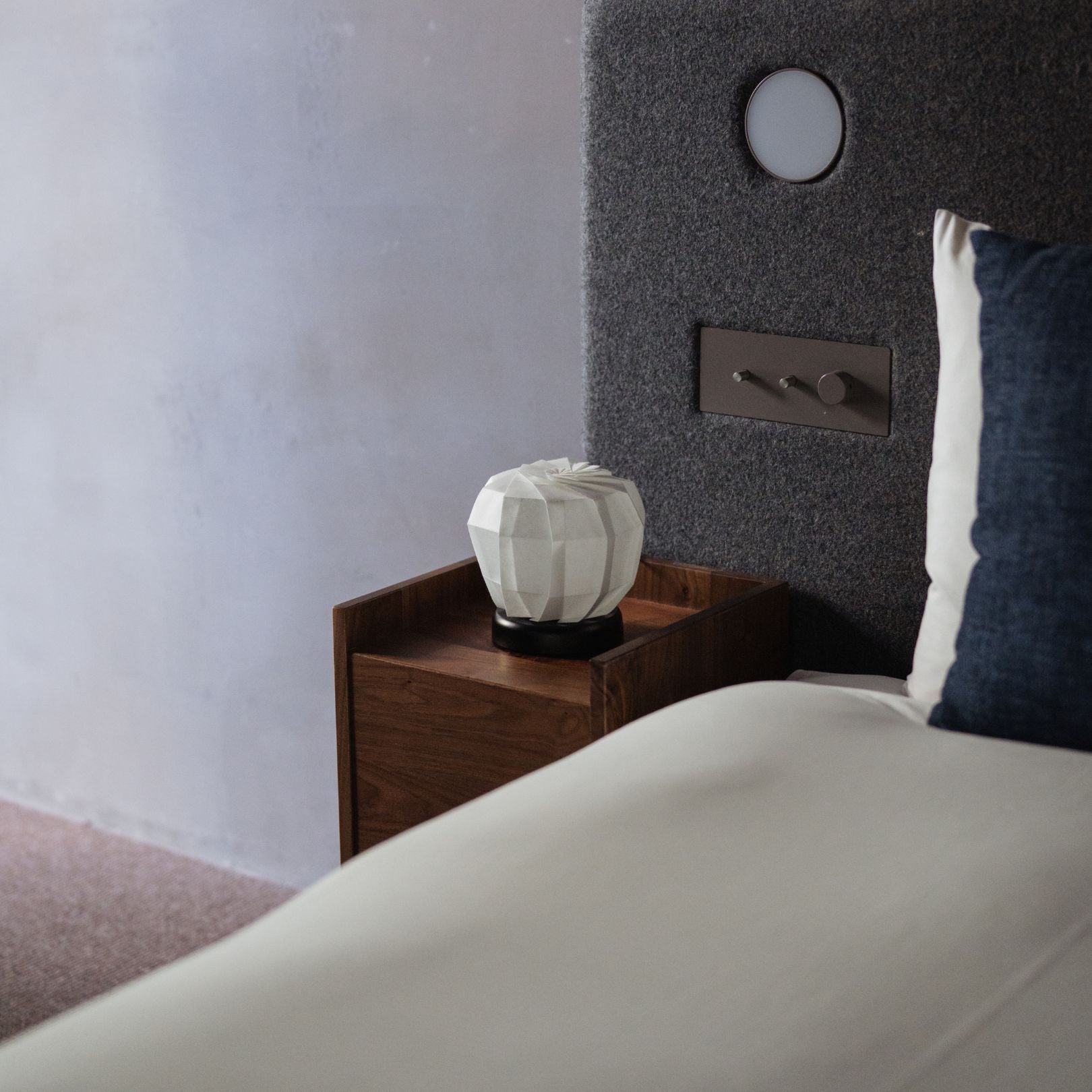 "Japanse papieren tafellamp 'Flower of Light maru M' op een houten nachtkastje in een Japanse slaapkamer"
