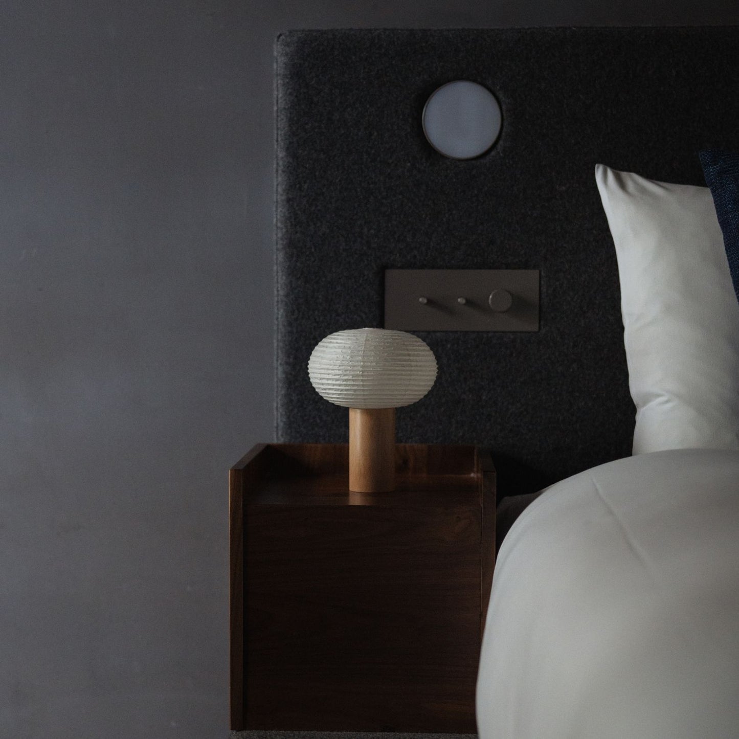 Japanische Papier Stehleuchte "TORCHIN OVAL" auf einem Nachttisch in einem Japandi-Schlafzimmer