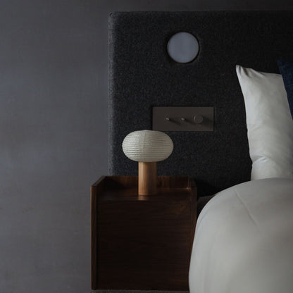 Japanische Papier Stehleuchte "TORCHIN OVAL" auf einem Nachttisch in einem Japandi-Schlafzimmer