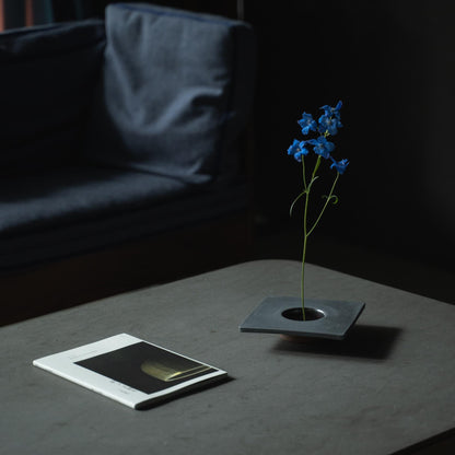 Nærbillede af en minimalistisk jern ikebana-vase, der viser kenzan (blomsterfrosk) til at arrangere blomster.