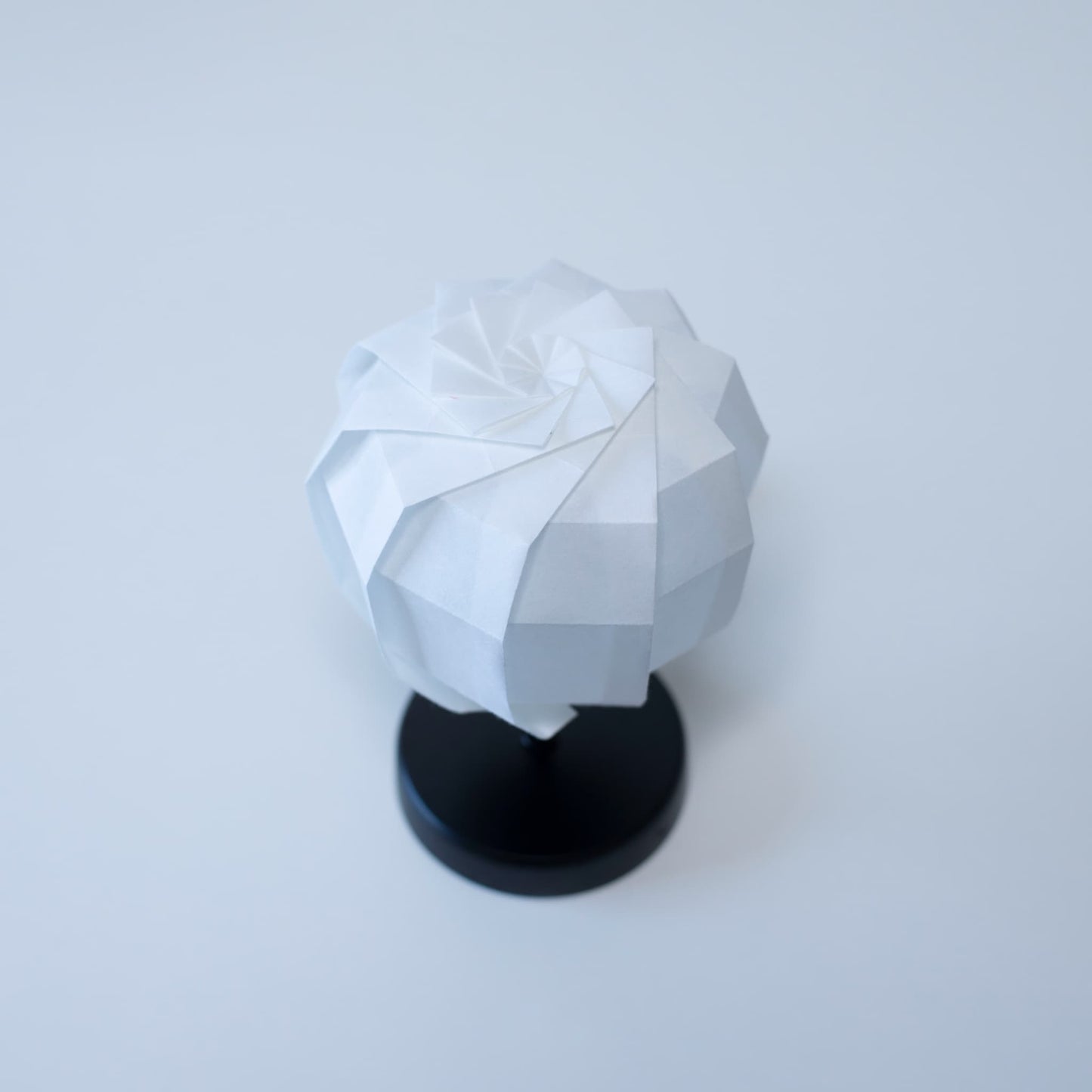 "Originele Tafellamp 'maru' met een zwarte standaard en een bolvormige witte lampenkap, vakkundig gevouwen van washipapier."