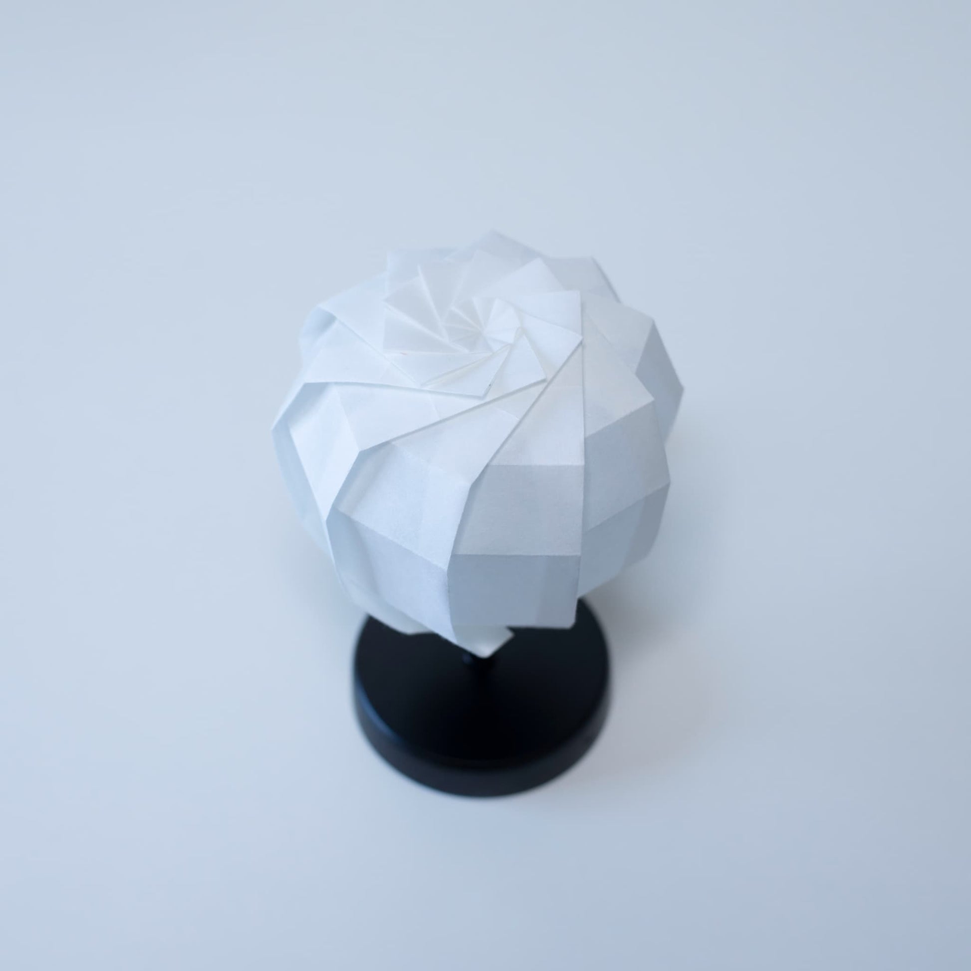 "Originele Tafellamp 'maru' met een zwarte standaard en een bolvormige witte lampenkap, vakkundig gevouwen van washipapier."