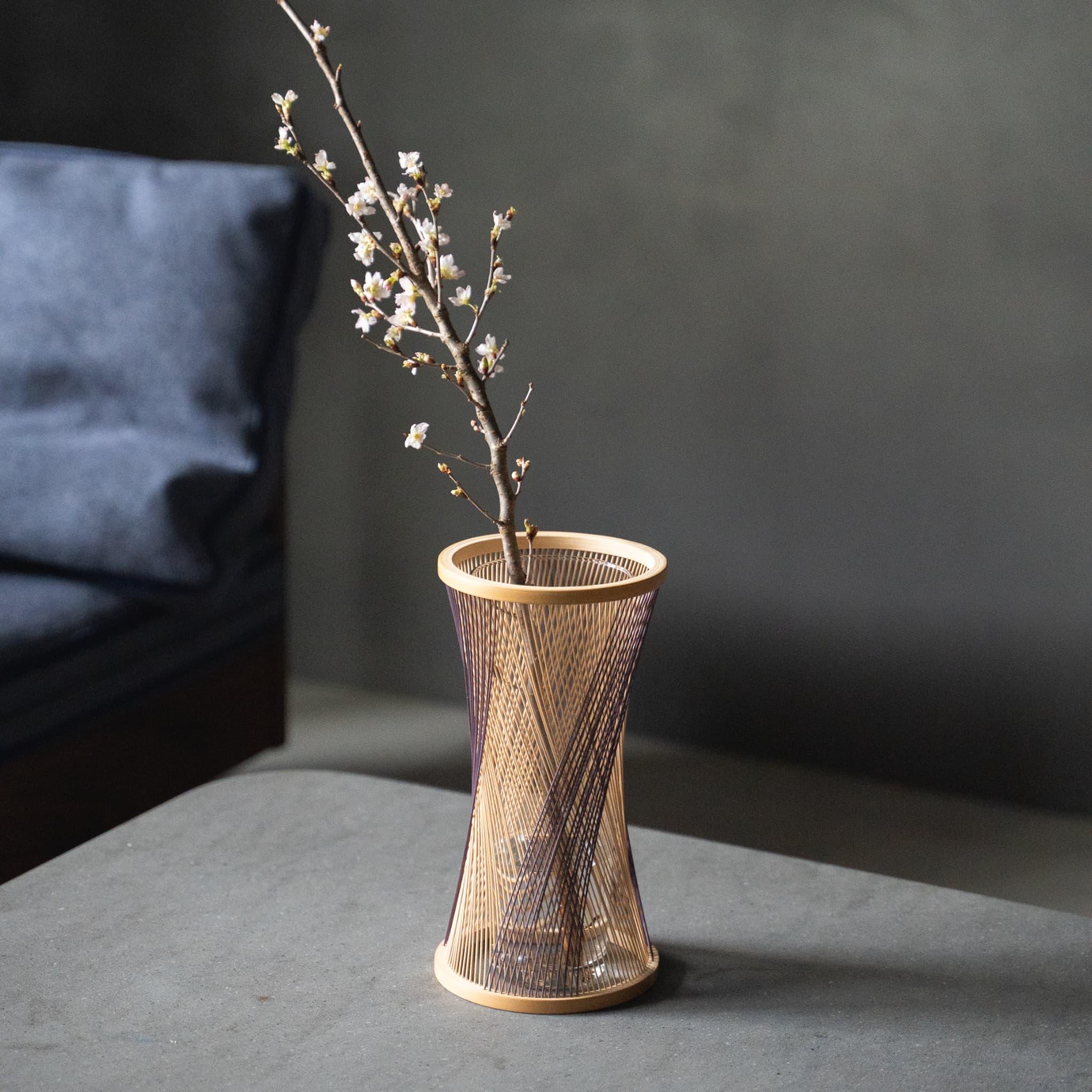 Håndlavet japansk bambus Ikebana-vase, omhyggeligt fremstillet af dygtige håndværkere ved hjælp af traditionelle bambusvævningsteknikker, der viser bambusens naturlige skønhed og elegance.