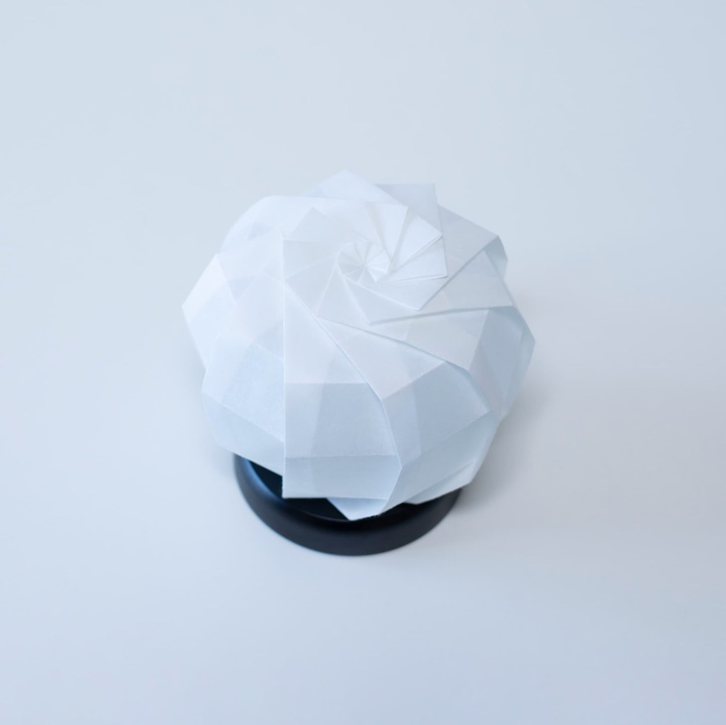 Stijlvolle Origami tafellamp met een zwarte voet en een witte sferische lampenkap van getextureerd washipapier.