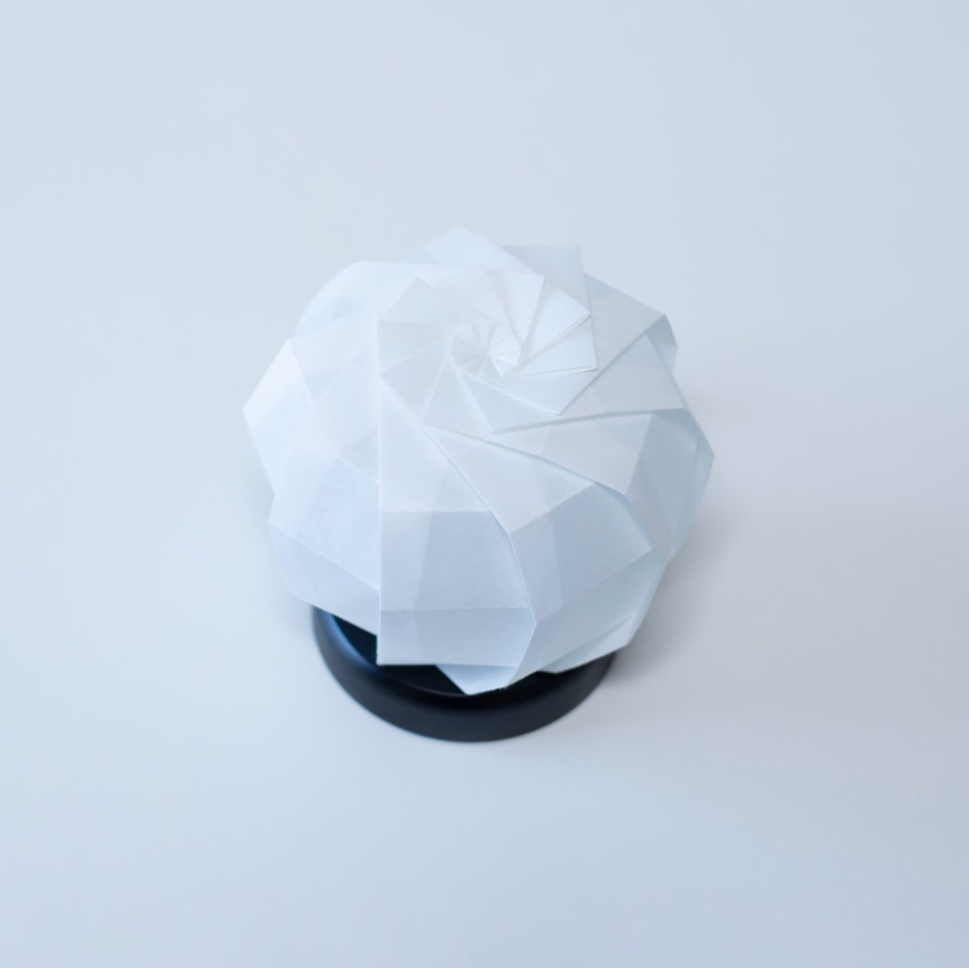 Stijlvolle Origami tafellamp met een zwarte voet en een witte sferische lampenkap van getextureerd washipapier.