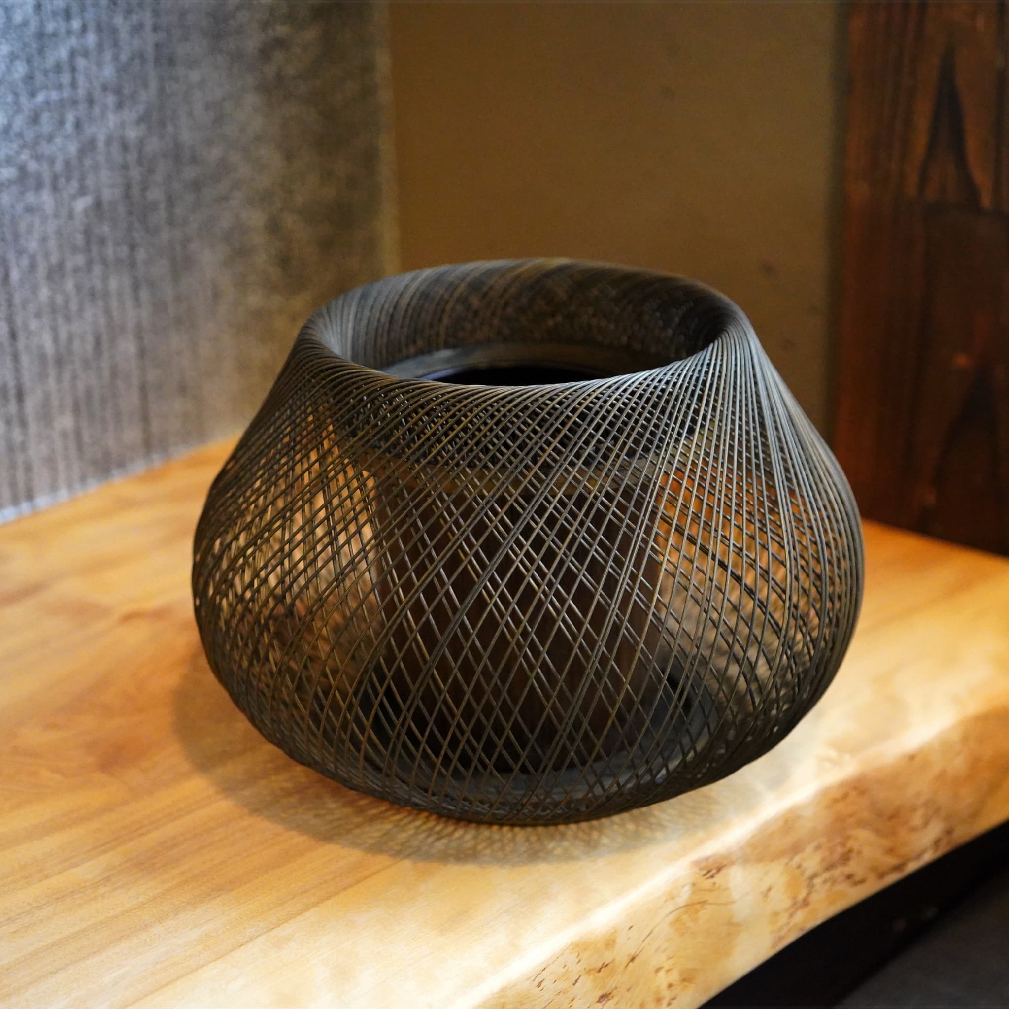 oval japansk ikebana-vase, der hviler på et japansk-stil træbord.